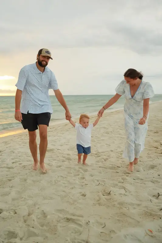 Family holding hands on the beach, photographed by Miranda Rae