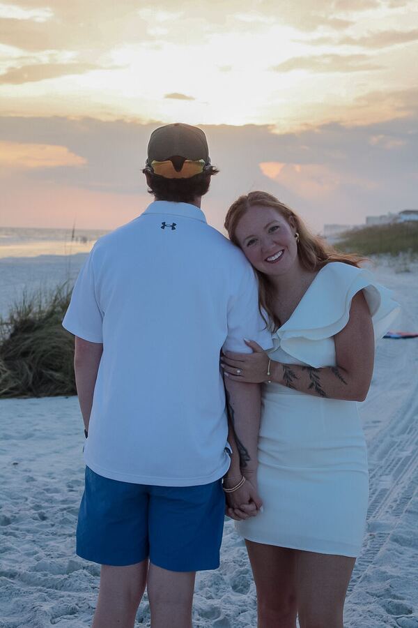 Couple holding hands watching the sunset over the beach